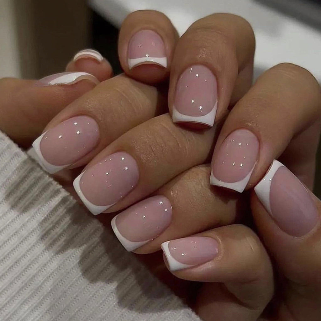 Short press-on nails: sheer pink base, white French tips, tiny sparkle dots