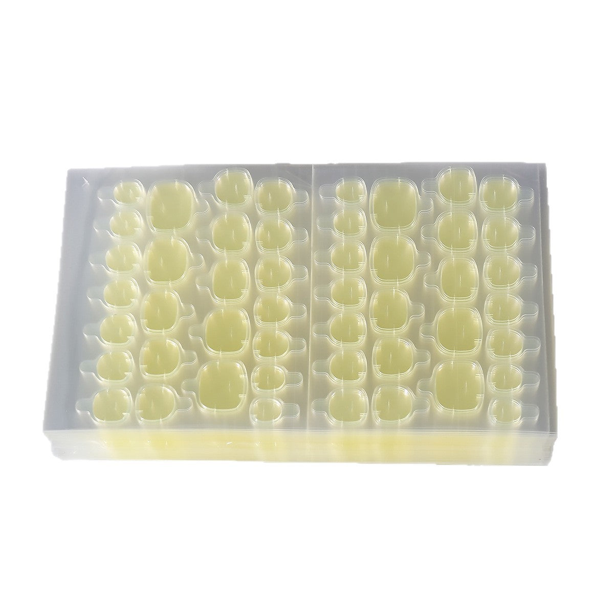 Large light yellow press-on nail tips set in a clear plastic storage box